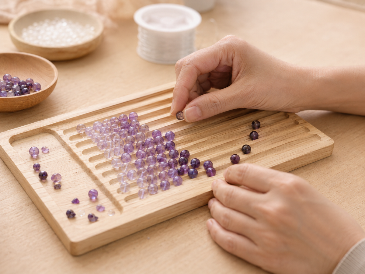 Hands grading amethyst beads into a color run