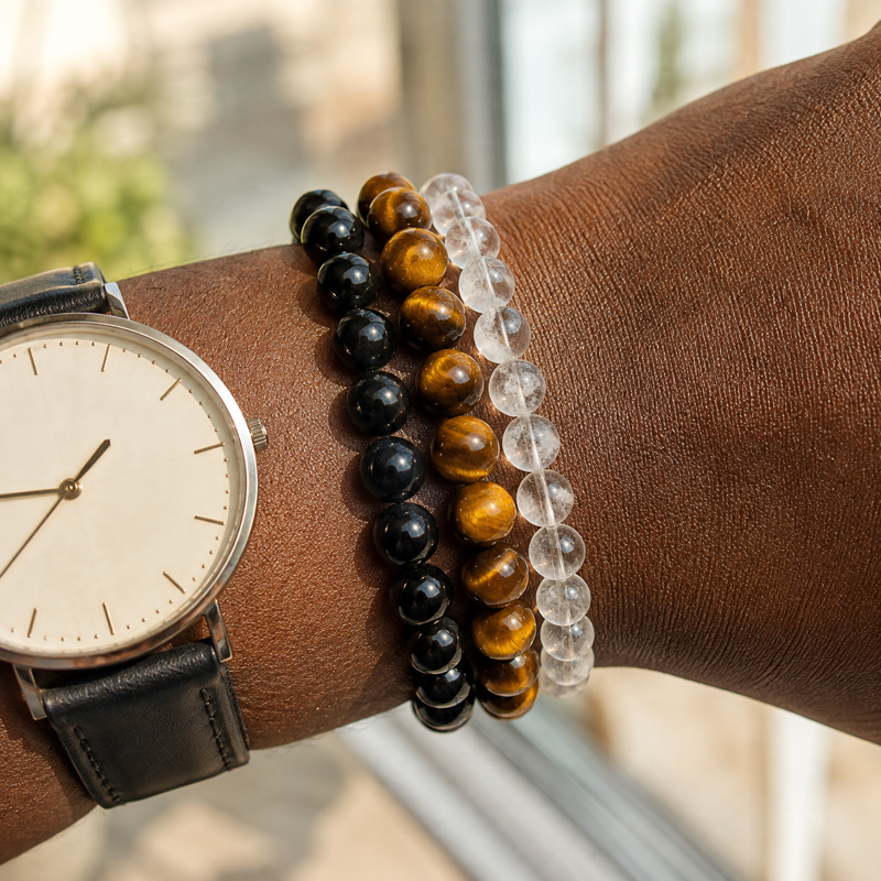 Three natural-stone bracelets stacked beside a watch